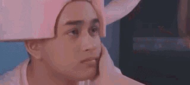 a woman is kissing another woman on the forehead while wearing a pink hat .