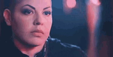a close up of a woman 's face with a shaved head looking at the camera .