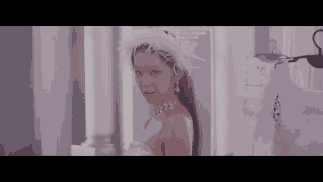 a woman is wearing a white dress and a white feathered headband .
