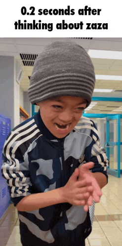a young boy wearing a gray beanie and a blue adidas jacket is clapping his hands