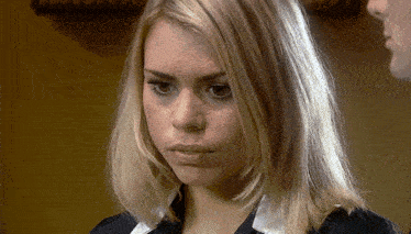 a close up of a blonde woman 's face with a man behind her