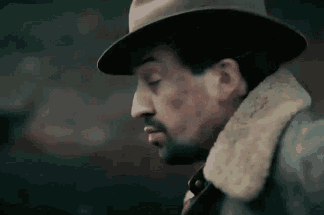 a close up of a man wearing a hat and a jacket