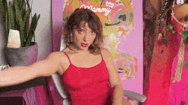 a woman in a red tank top is sitting in front of a painting that says mammy
