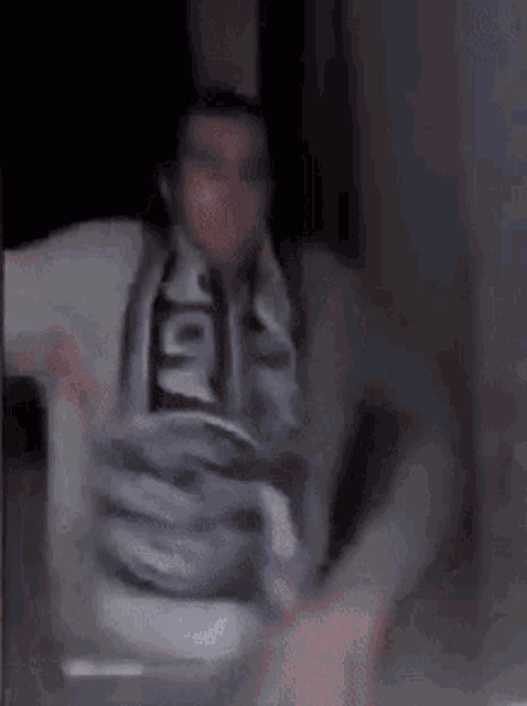 a man wearing a scarf is standing in a dark room with his arms outstretched .