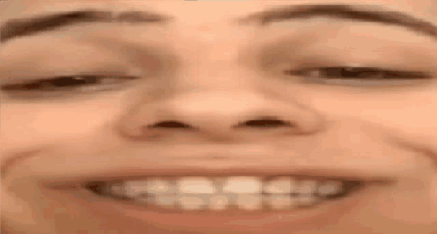a close up of a person 's face with their eyes closed and their teeth showing .