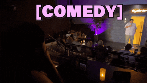 a man stands in front of a microphone with the word comedy above him