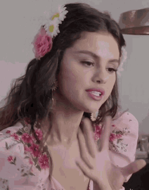 a woman wearing a pink floral dress with flowers in her hair .