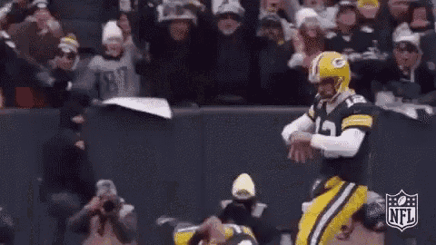 a football player is kicking a ball in front of a crowd of people .