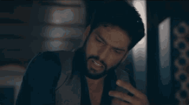a man with a beard is taking a picture of himself with his phone in a dark room .