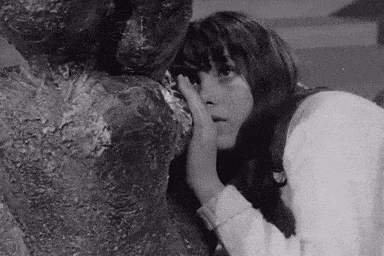 a black and white photo of a woman standing next to a statue .
