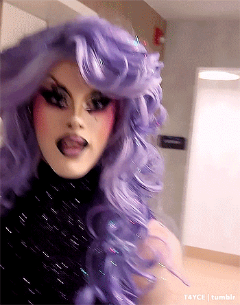 a woman in a purple wig is sticking out her tongue .