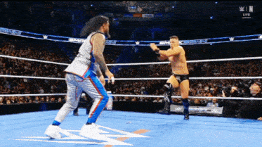 two wrestlers in a wrestling ring with a sign that says n live