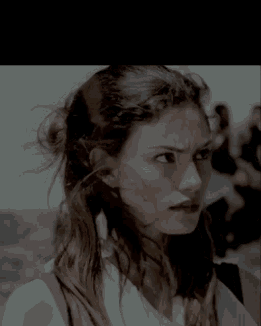 a close up of a woman 's face with the wind blowing her hair