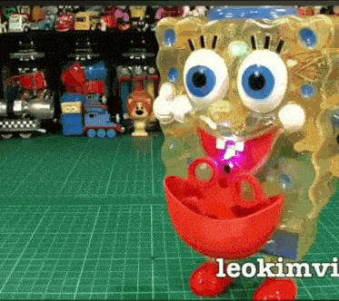 a spongebob toy is sitting on a green cutting mat next to other toys