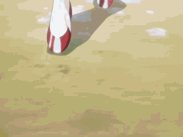 a pair of red and white shoes are walking on a sandy surface