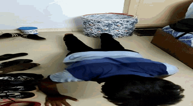 a person in a blue shirt is laying on the floor with their legs crossed