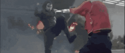 a man is kicking another man in the face in a black and white video .