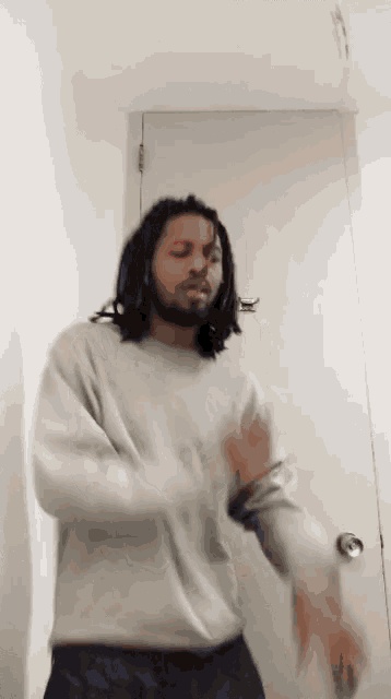 a man with dreadlocks is standing in front of a door .