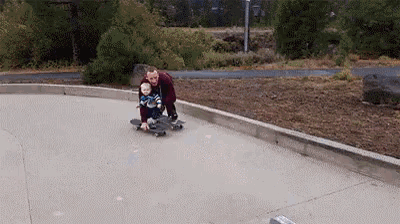a man is pushing a baby on a skateboard .
