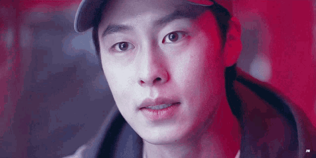a close up of a man 's face wearing a baseball cap and a hoodie .