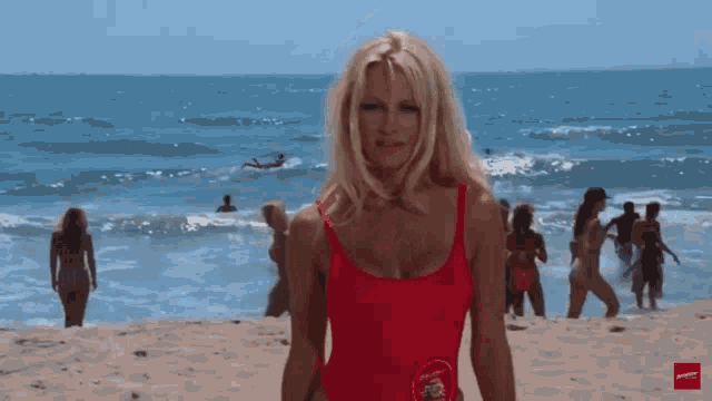 a woman in a red swimsuit stands on the beach