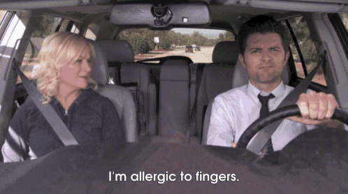 a man and a woman are sitting in a car and the man is saying i 'm allergic to fingers