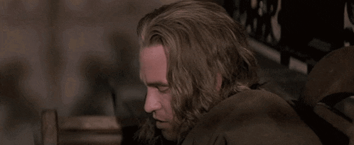 a man with long hair looks over his shoulder