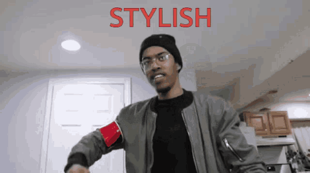 a man wearing a beanie and glasses is standing in front of a sign that says stylish on it