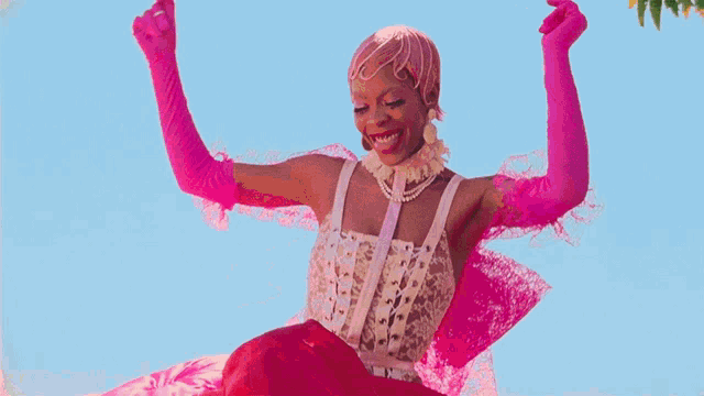 a woman wearing pink gloves and a white top is smiling