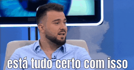 a man with a beard is sitting in front of a television with the words esta tudo certo com isso above him