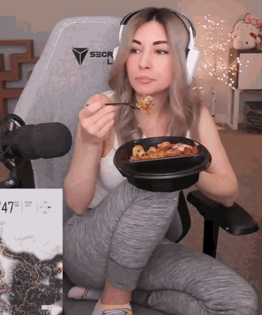 a woman sitting in a gaming chair eating a meal