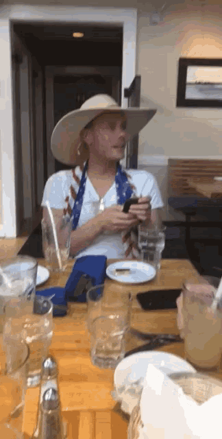 a man wearing a cowboy hat is sitting at a table