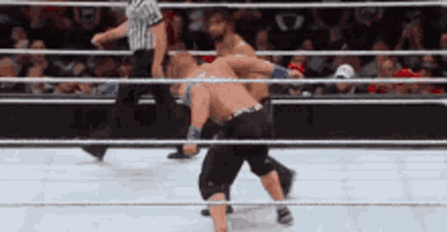 two men are wrestling in a ring with a referee