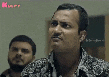 a man with a mustache is making a funny face while another man watches .