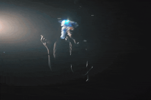 a woman in a dark room is holding a blue object in her hand