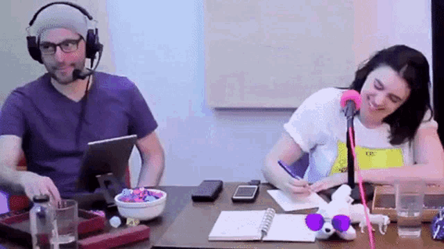 a man and a woman are sitting at a table with a microphone .