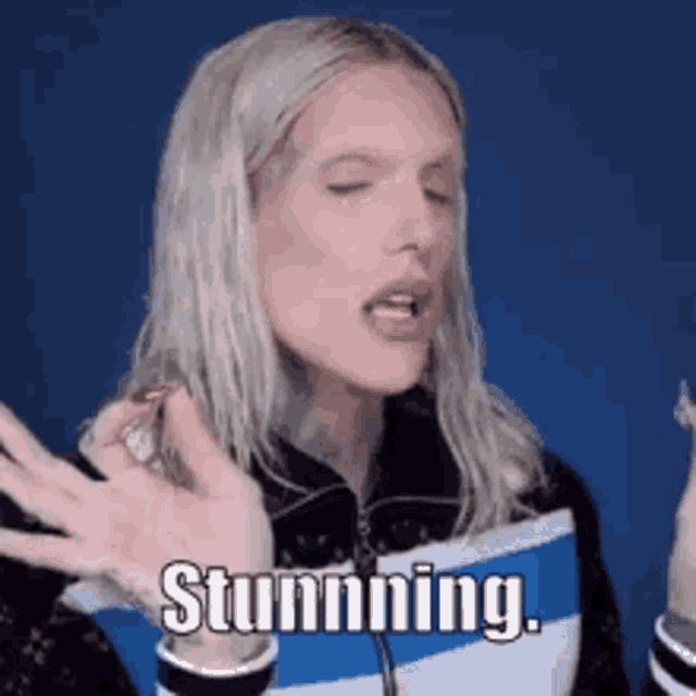 a woman with long blonde hair is holding a bag and saying `` stunning '' .