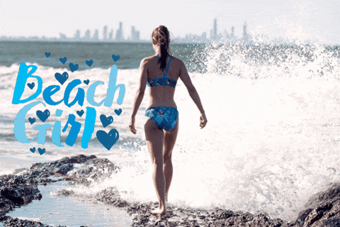 a woman in a bikini stands on rocks near the ocean with the words beach girl written in blue