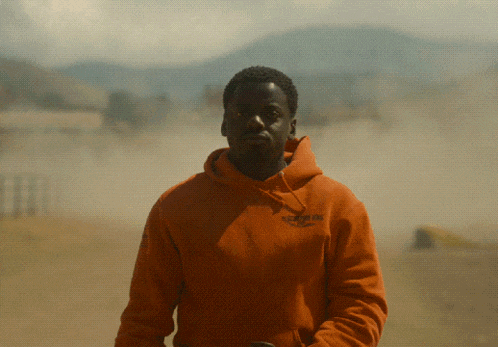 a man wearing an orange hoodie that says essentials on it
