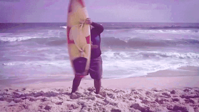 a man carrying a surfboard on the beach with a red bull logo on it