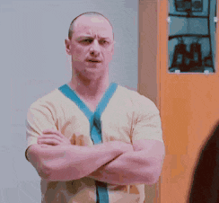 a man with his arms crossed is standing in front of a cabinet .