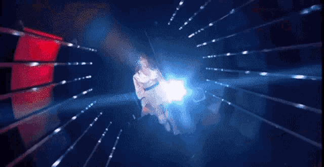 a woman in a white dress is dancing on a stage in a dark room .