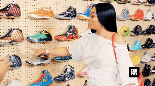 a woman stands in front of a wall of shoes with a com flex logo on the bottom