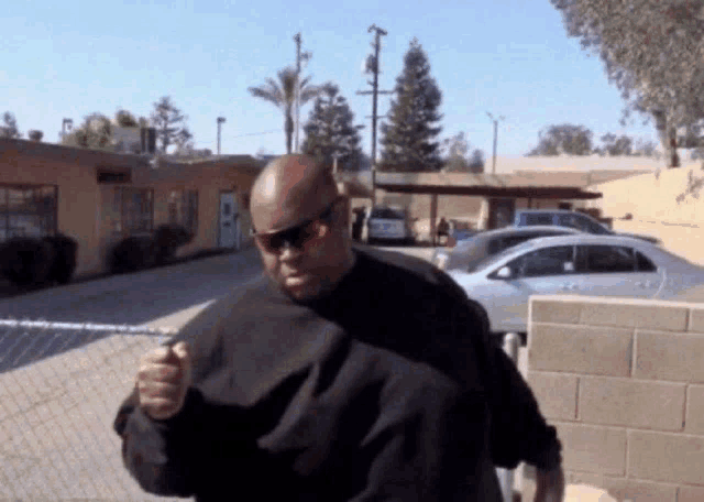 a man wearing sunglasses and a black shirt stands in front of a building