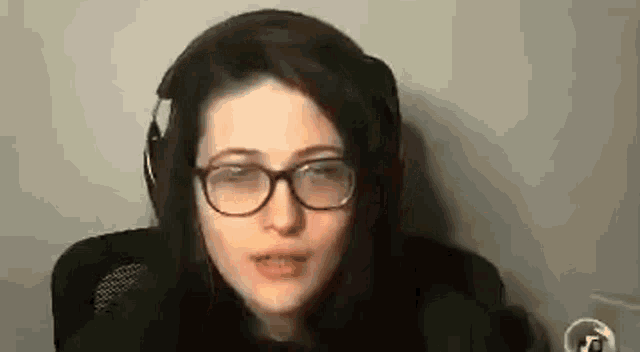 a young woman wearing glasses and headphones is sitting in a chair .