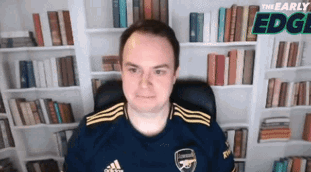 a man wearing an adidas shirt is sitting in front of a library