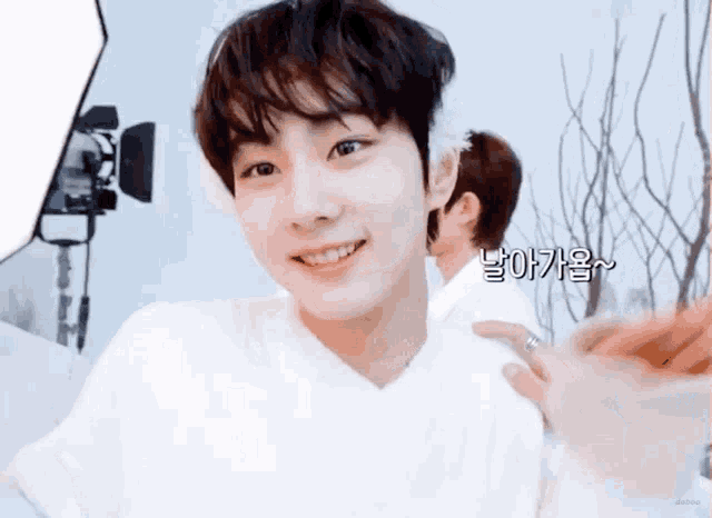 a young man in a white shirt is smiling and looking at the camera while another person holds his arm .