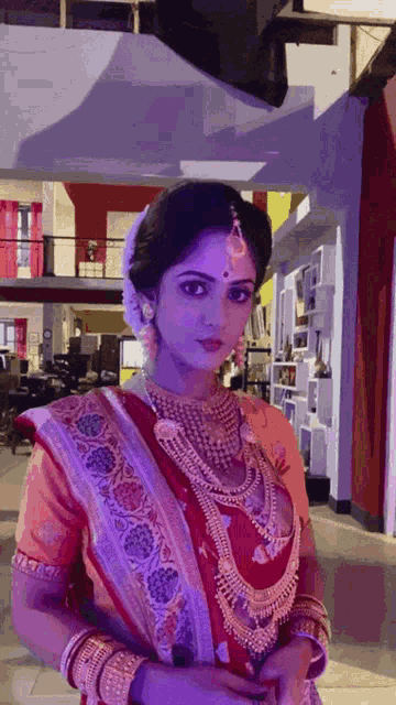 a woman in a red and gold dress is standing in a room with purple lights