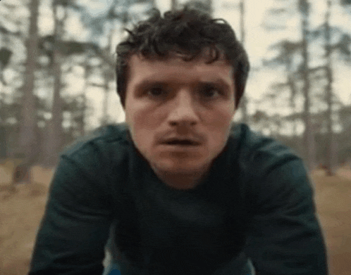a close up of a man 's face in a forest looking at the camera .
