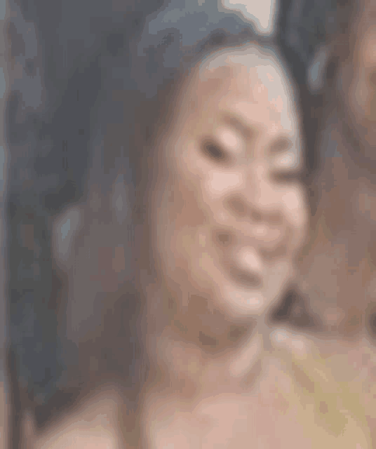 a blurry picture of a woman smiling and wearing a yellow top .
